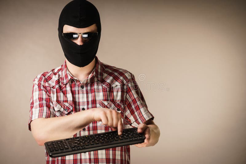 Man wearing balaclava holding keyboard stock images