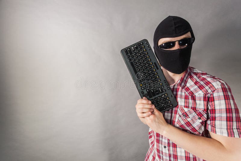 Man wearing balaclava shooting from keyboard stock photo