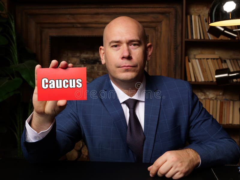 Man wearing blue business suit and showing blank red business card with written text Caucus . Blurred background. Horizontal