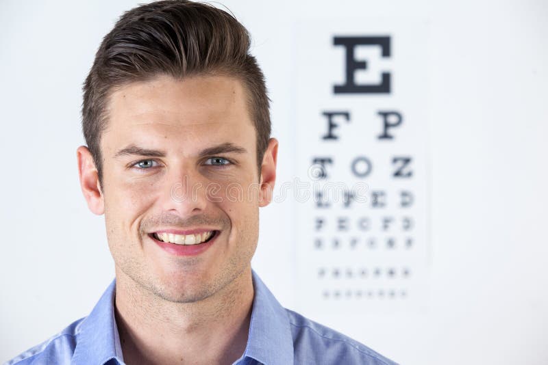Man Wearing Contact Lens With Eye Chart In Background Stock Photo