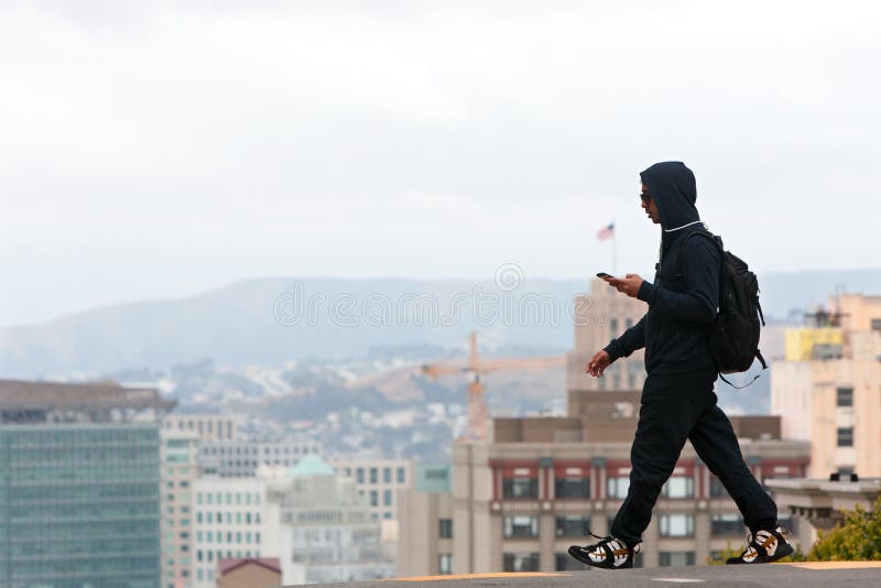 Man Wearing Hoodie Crosses Street In Contemporary San Francisco Scene
