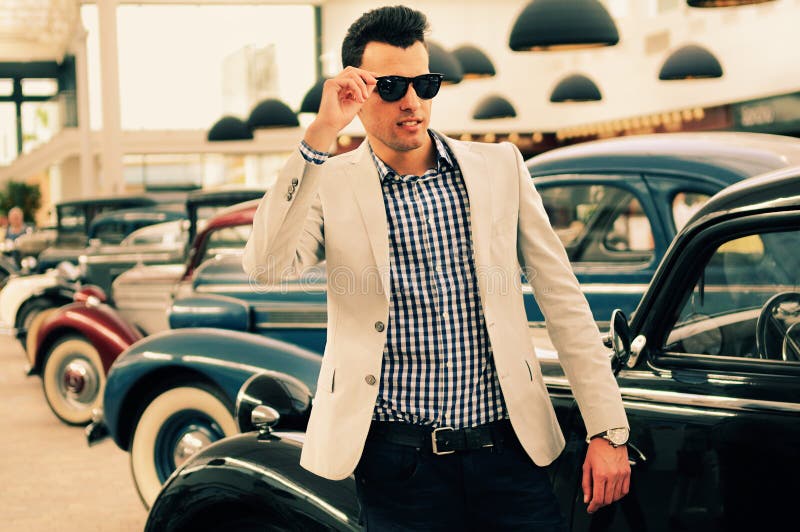 Man wearing jacket and shirt with old cars