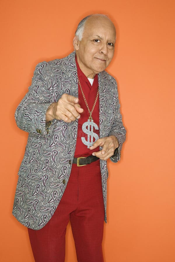 Mature adult Caucasian male wearing money sign necklace and pointing. Mature adult Caucasian male wearing money sign necklace and pointing.