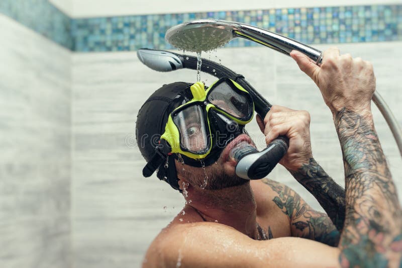 A Man Wearing a Scuba Mask in the Shower is Doused with Water Stock