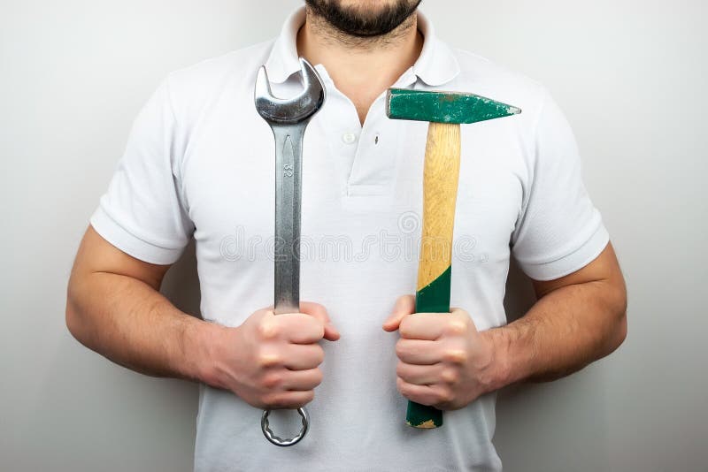A man in a white t-shirt with a hammer and a wrench royalty free stock photo A man in a white t-shirt with a hammer and a wrench royalty free stock photo