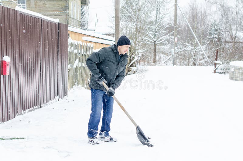 Man in Winter Clothes Clearing Snow from Path with Shovel. Winter Time