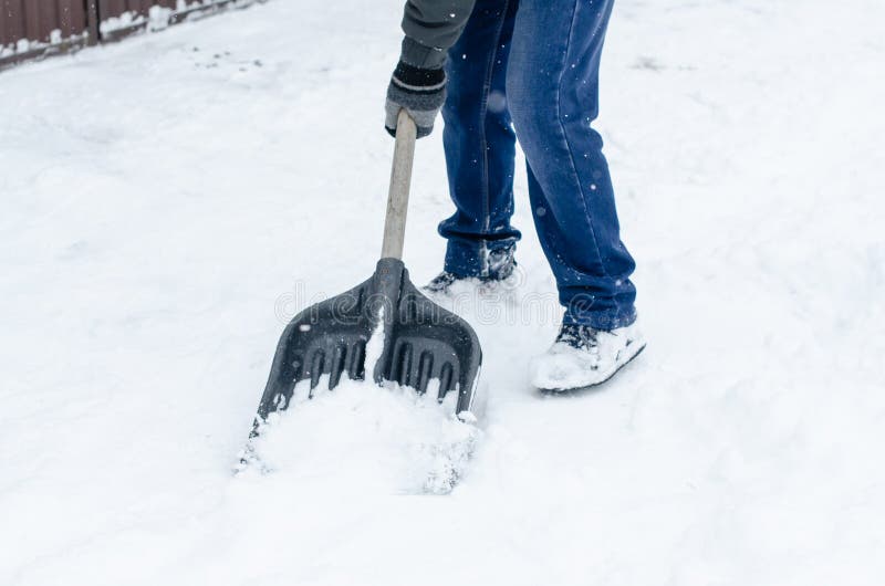 Man in Winter Clothes Clearing Snow from Path with Shovel. Winter Time