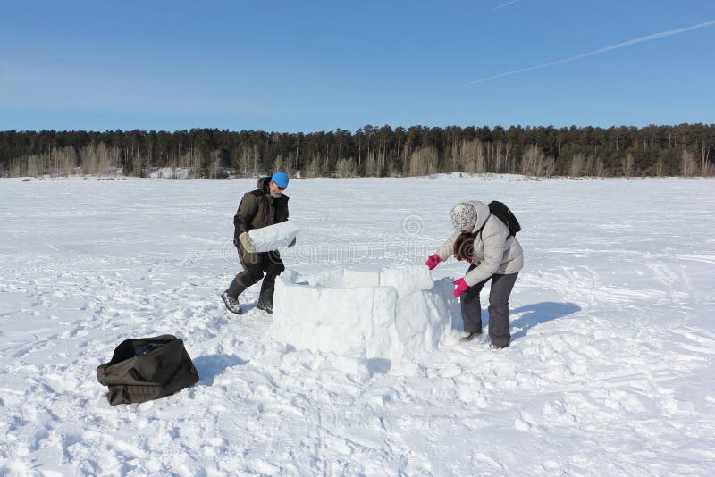 Man and woman building an igloo in a snowy glade