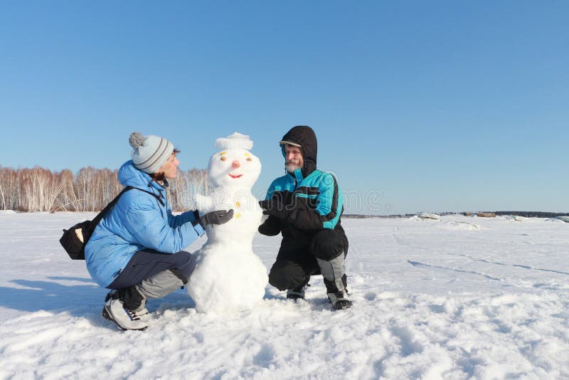 The man and woman building a snowman