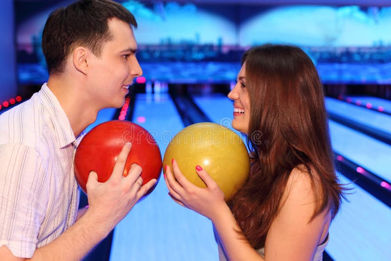 Man and woman hold balls in bowling