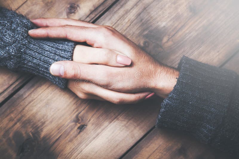 Man and woman holding hands at a wooden table stock photography