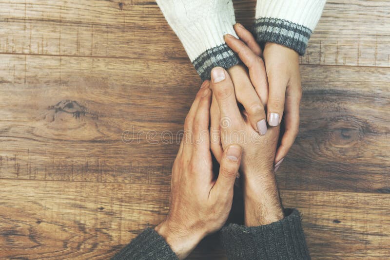 Man and a woman holding hands at a wooden table royalty free stock photography Man and a woman holding hands at a wooden table royalty free stock photography