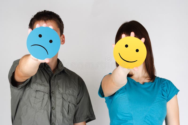 Man and woman holding sad and fun smiles