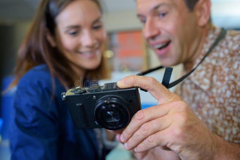 Man and woman looking at display digital camera