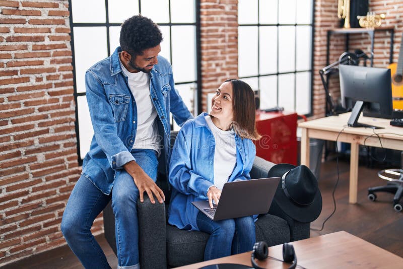 Man and woman musicians smiling confident using laptop at music studio stock photography