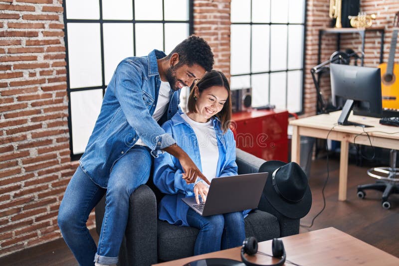 Man and woman musicians smiling confident using laptop at music studio stock photography