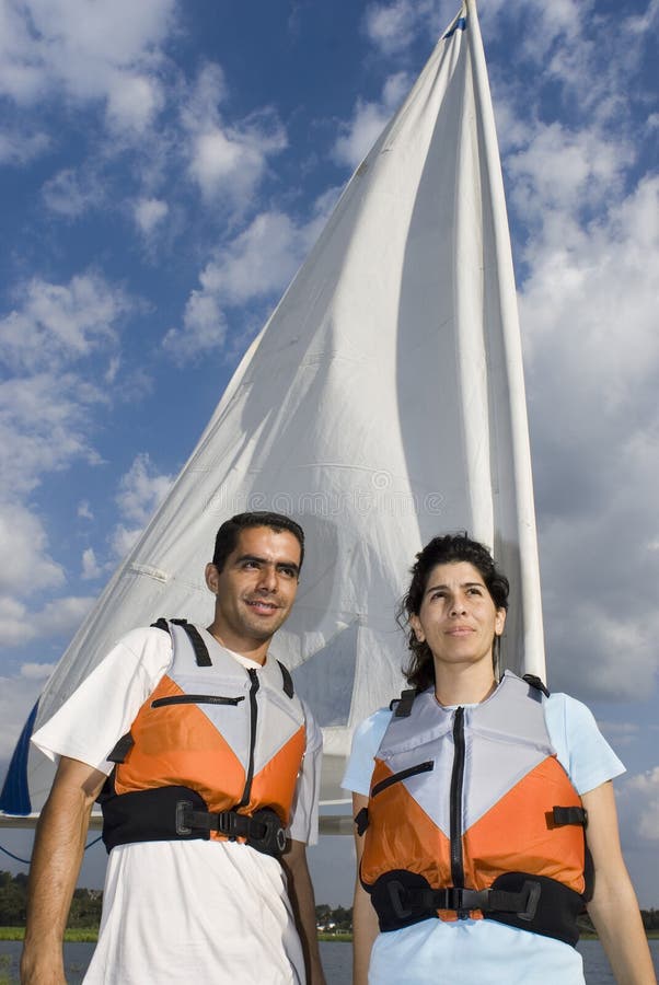 Man and Woman Next to Sailboat on Water - Vertical