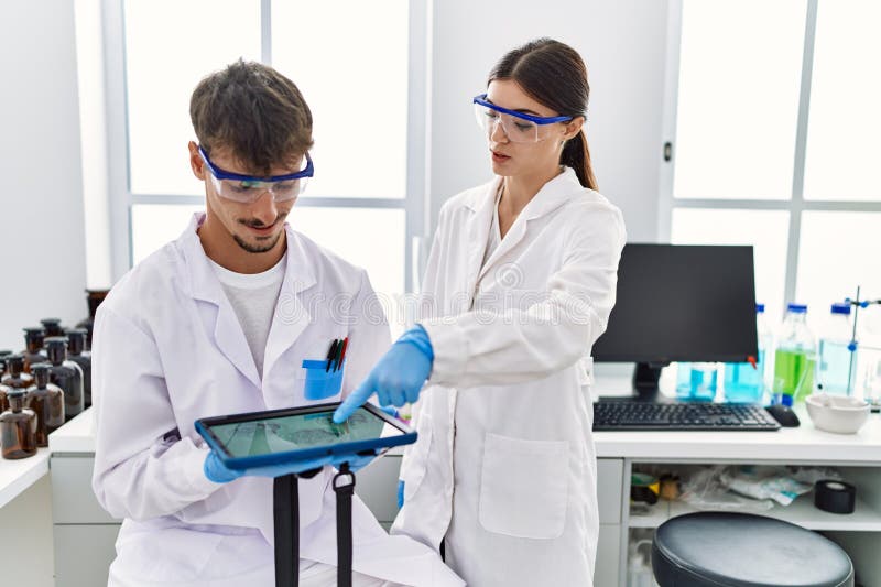 Man and Woman Partners Wearing Scientist Uniform Using Touchpad with