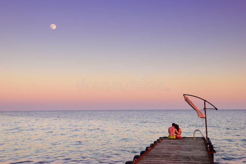 Man and woman on a pier in the moonlight stock images