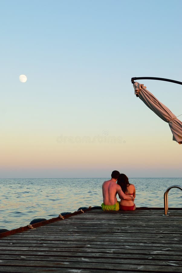 Man and woman on a pier on sunse stock photo