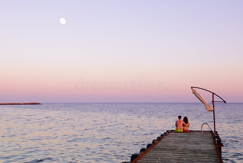 Man and woman on a pier on sunset stock photo