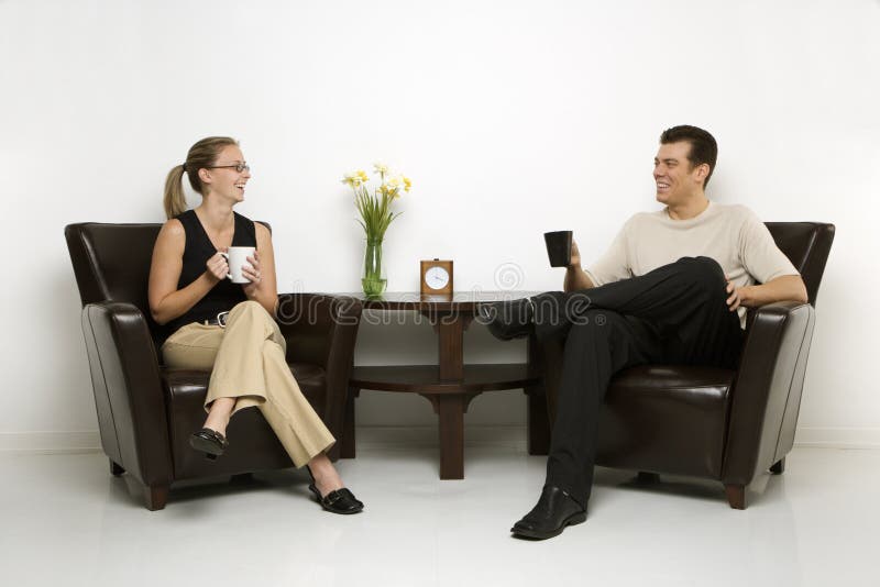 Caucasian mid-adult man and woman sitting in armchairs drinking coffee. Caucasian mid-adult man and woman sitting in armchairs drinking coffee.