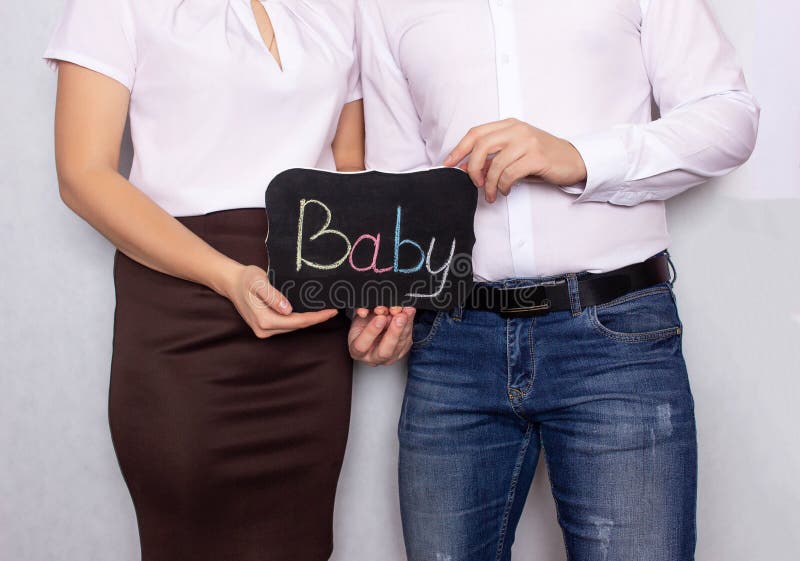 A man and a woman stand with a sign on which the baby is written, problems with the conception of children, male and female infertility, disease