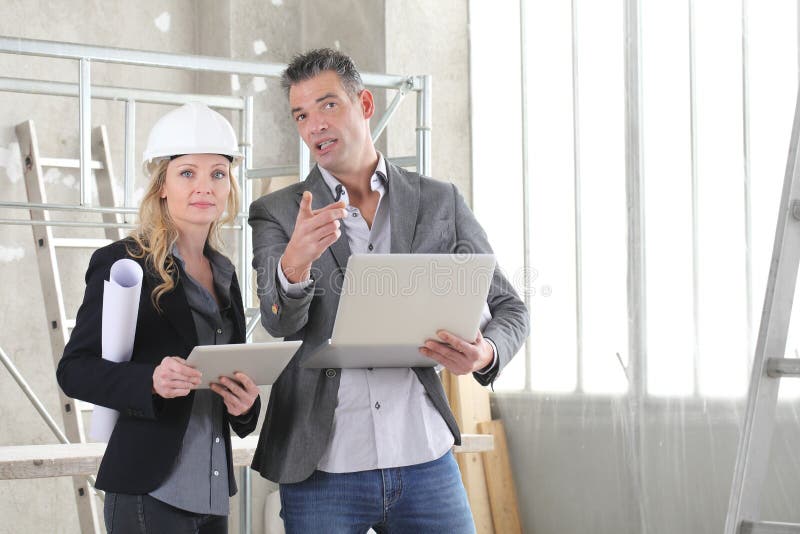 Man and woman architects or engineers with computer work together in the inside the construction building site royalty free stock photo