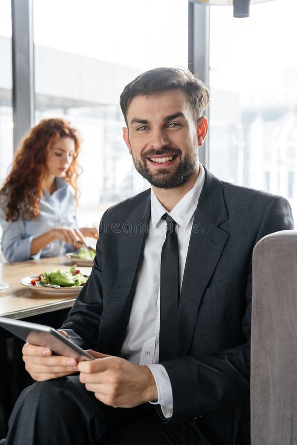Businesspeople having business lunch at restaurant sitting man close-up holding digital tablet looking camera smiling stock photography Businesspeople having business lunch at restaurant sitting man close-up holding digital tablet looking camera smiling stock photography
