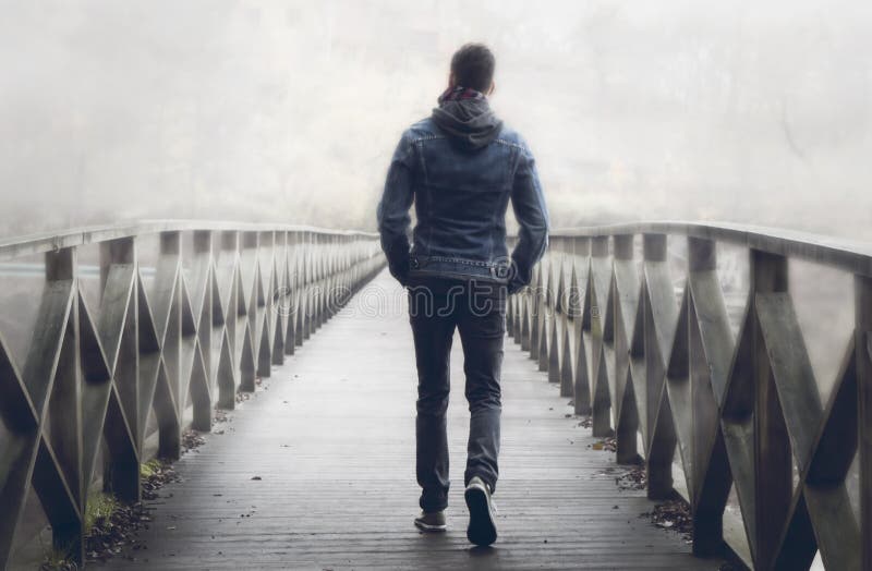 Man on wooden bridge a misty autumn day.