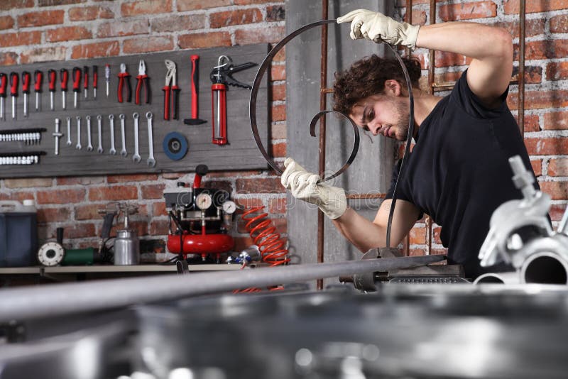 Man work in home workshop garage with bench grip vise fix a metal on the workbench full of wrenches, diy and craft concept.