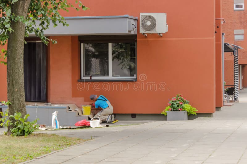 A male worker diligently lays an imitation of stone on the wall near the entrance to the building. The design of the entrance group with a brick. Bricklayer tiler stock images, royalty-free photos and pictures