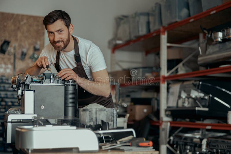 Man worker repair a coffee machine in own workshop and looking camera royalty free stock images
