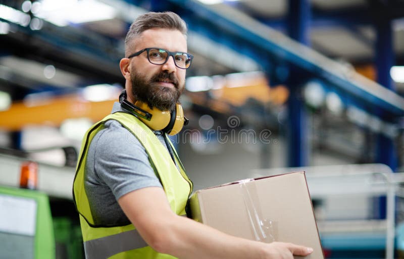 Man Worker Working In Industrial Factory Or Warehouse. Stock Photo