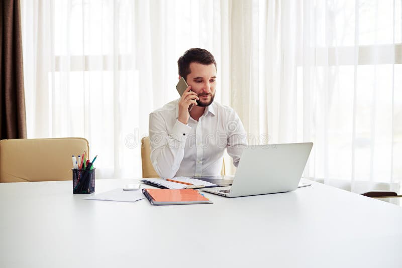 Man working and calling someone on the phone in the modern offic.