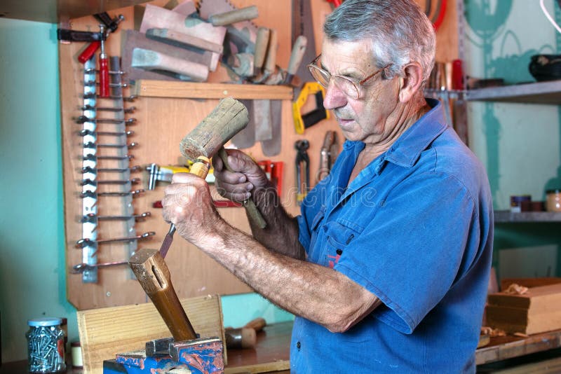 Carpenter in the workshop handling a chisel and a hammer on a piece of wood. Carpenter in the workshop handling a chisel and a hammer on a piece of wood