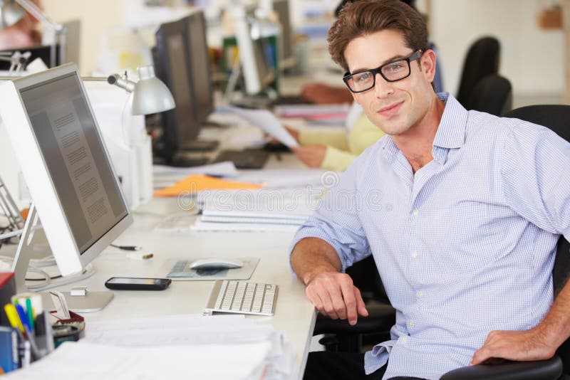 Man Working At Desk In Busy Creative Office