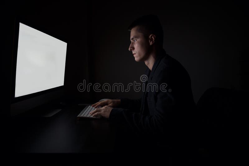 Man working looking to the monitor screen and typing on computer keyboard during the night work in the office stock images