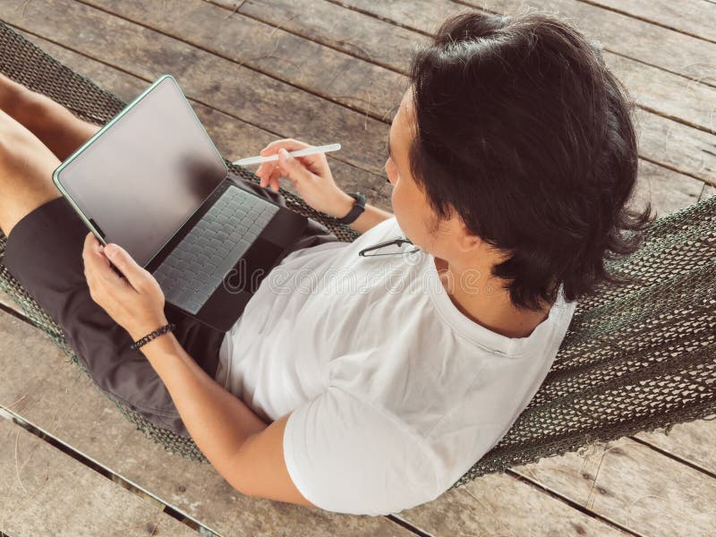Man working online with computer on the hammock by the beach stock photos