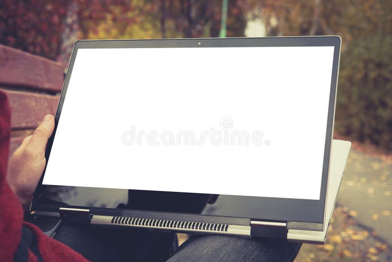 A man is working using laptop at park. outdoor, blank screen for background. tablet transformer in a man`s hand royalty free stock image