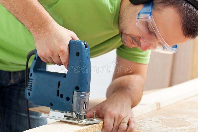 Man working wood with electric saw ans safety goggles