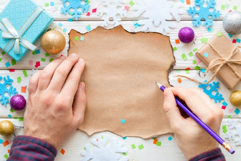 Man writes in a list of wishes on the background of Christmas toys and gifts
