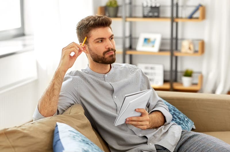 Man writing to notebook and thinking at home