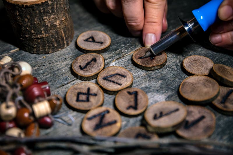 Man writing wooden runes with an pyrography or pokerwork