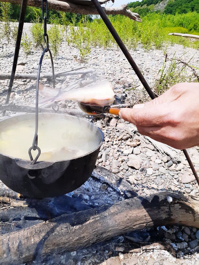 Man& x27 χέρι του s με ένα ξύλινο κουτάλι και ένα ψάρι σε το ένα δοχείο σιδήρου με μια νόστιμη σούπα ψαριών φιαγμένη από βρασμένα στοκ εικόνες Man& x27 χέρι του s με ένα ξύλινο κουτάλι και ένα ψάρι σε το ένα δοχείο σιδήρου με μια νόστιμη σούπα ψαριών φιαγμένη από βρασμένα στοκ εικόνες