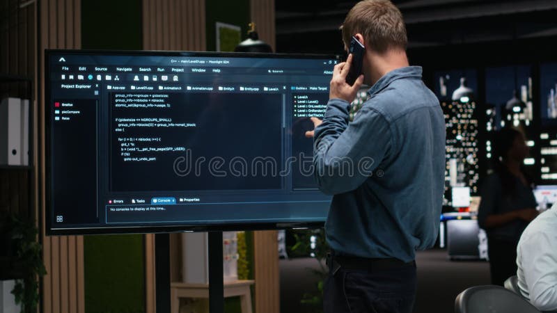 Manager analyzes code on screen, makes phone call stock video