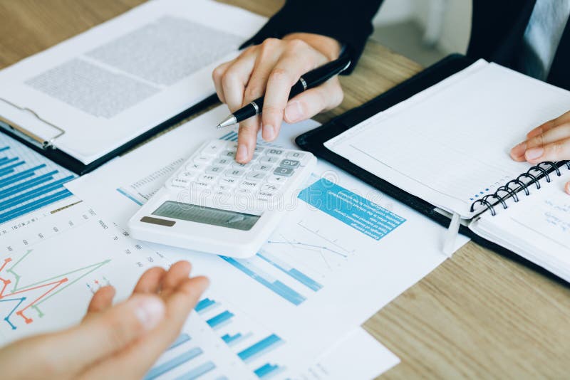 Manager calculates about the company finances by pressing on the calculator on the table with the employee explaining the summary stock photos Manager calculates about the company finances by pressing on the calculator on the table with the employee explaining the summary stock photos