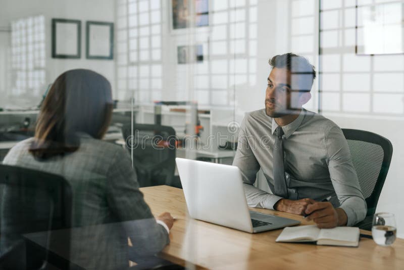 Manager die een baanaanvrager binnen van zijn bureau interviewen stock afbeeldingen Manager die een baanaanvrager binnen van zijn bureau interviewen stock afbeeldingen
