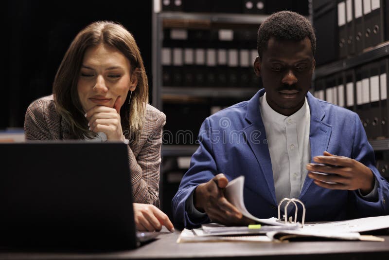 Depository managers working in corporate repository, analyzing management research discovering new accountancy record. Diverse businesspeople reading bookkeeping report in in storage room. Depository managers working in corporate repository, analyzing management research discovering new accountancy record. Diverse businesspeople reading bookkeeping report in in storage room