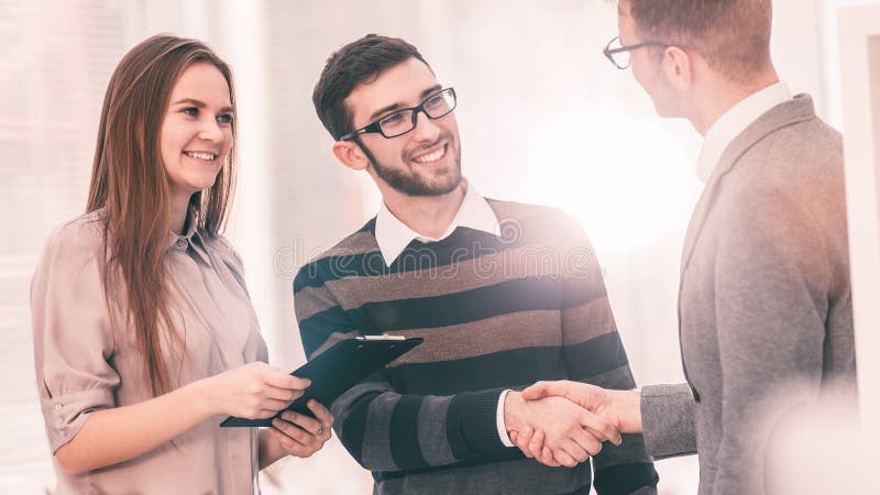 Manager shakes hands with the employee in a workplace in a modern office royalty free stock photography Manager shakes hands with the employee in a workplace in a modern office royalty free stock photography